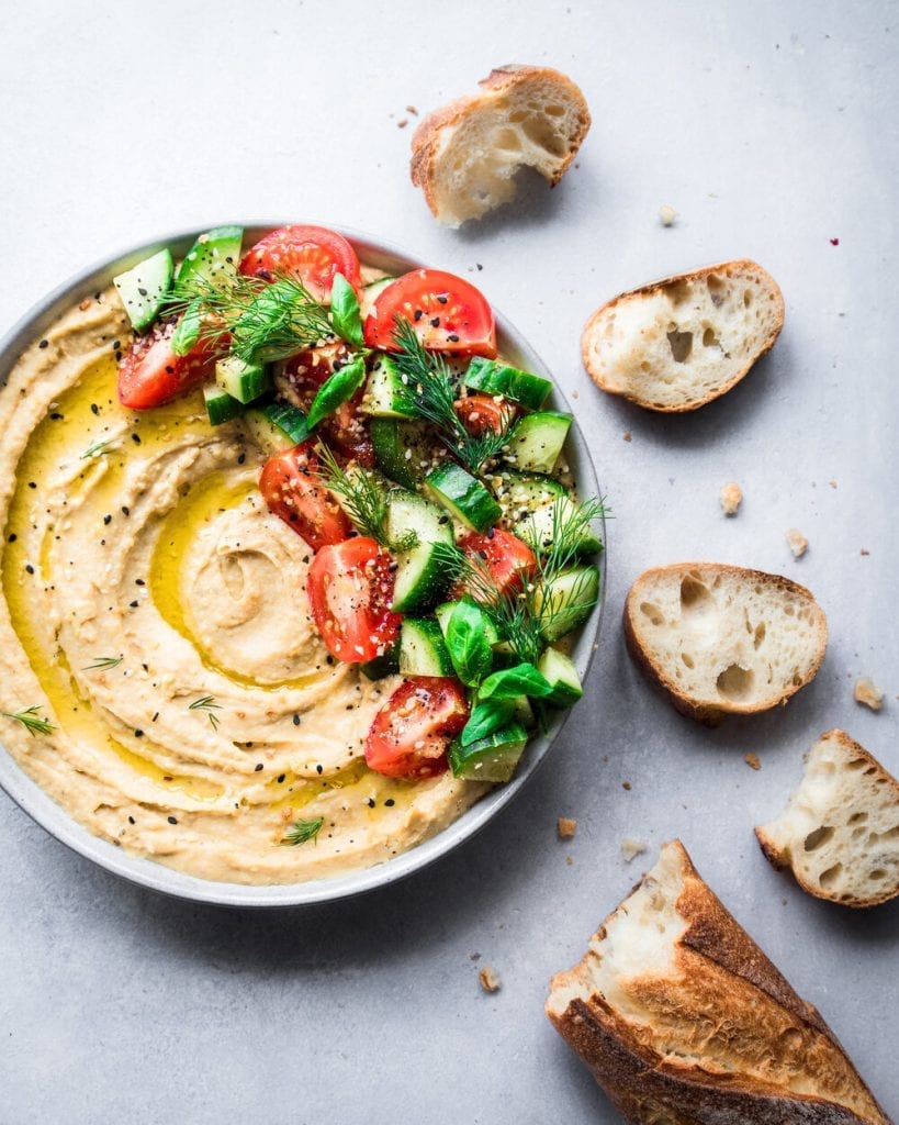 creamy hummus swirled with olive oil, topped with cucumbers and tomatoes