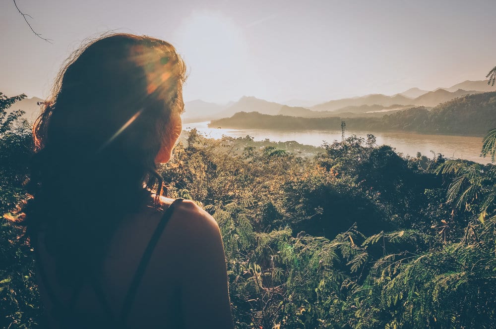 Woman looking out toward a river and mountains in Laos.