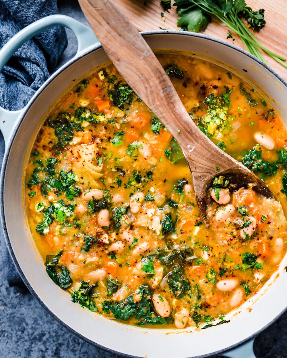 white bean soup with kale and gremolata in dutch oven with wooden spoon