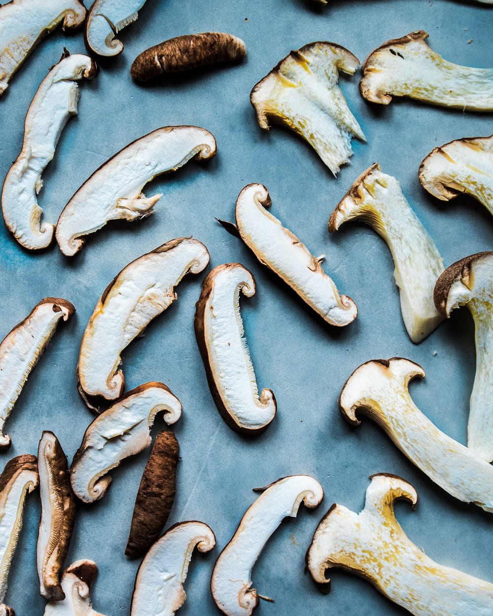 Thinly sliced mushrooms on a piece of parchment paper.