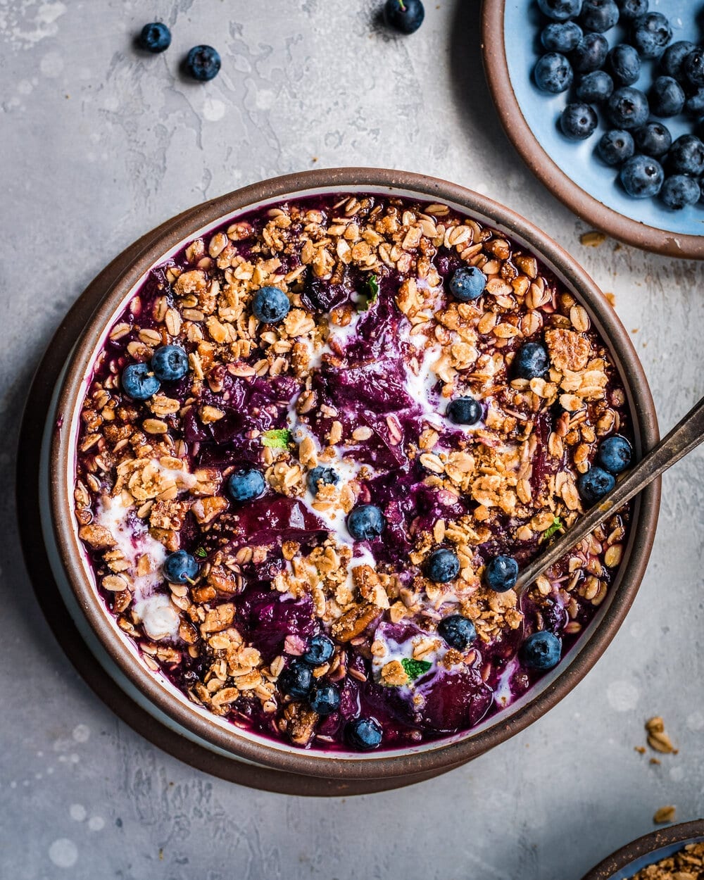 Berry Crisp mixed with ice cream in a bowl on a grey table.