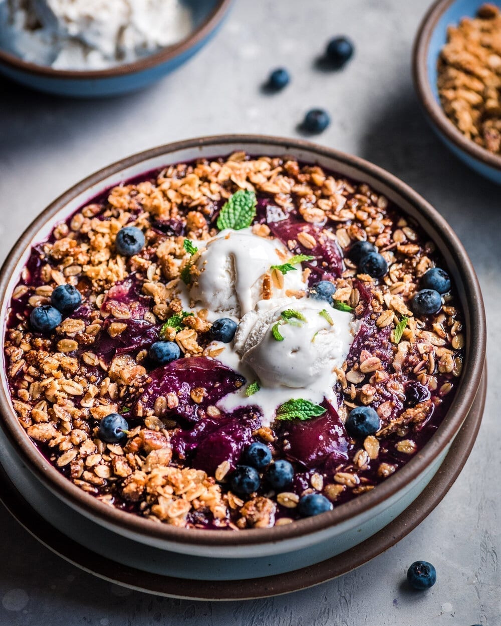 berry crisp in bowl with ice cream.