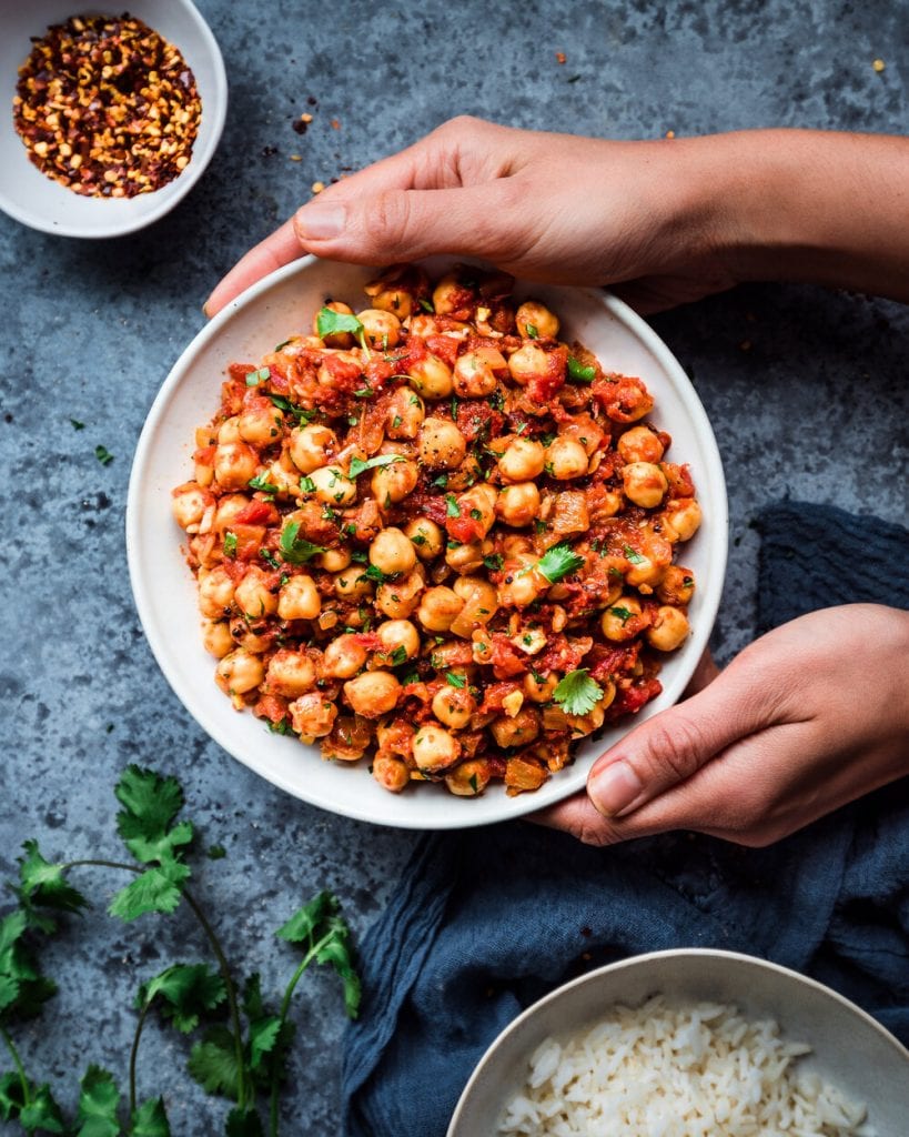 bowl of Indian chana masala framed by hands
