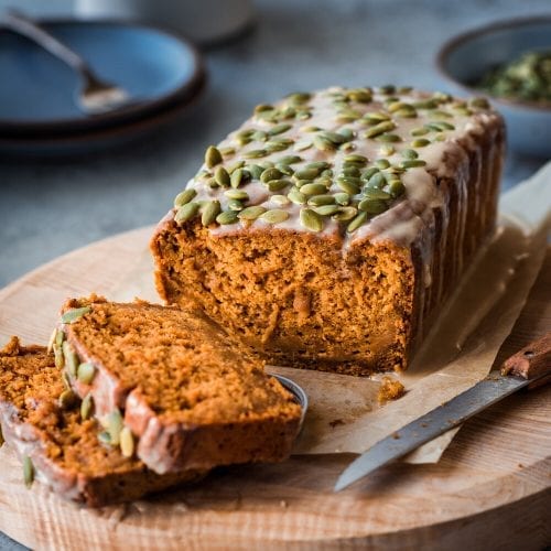 vegan pumpkin bread with icing on a wooden cutting board