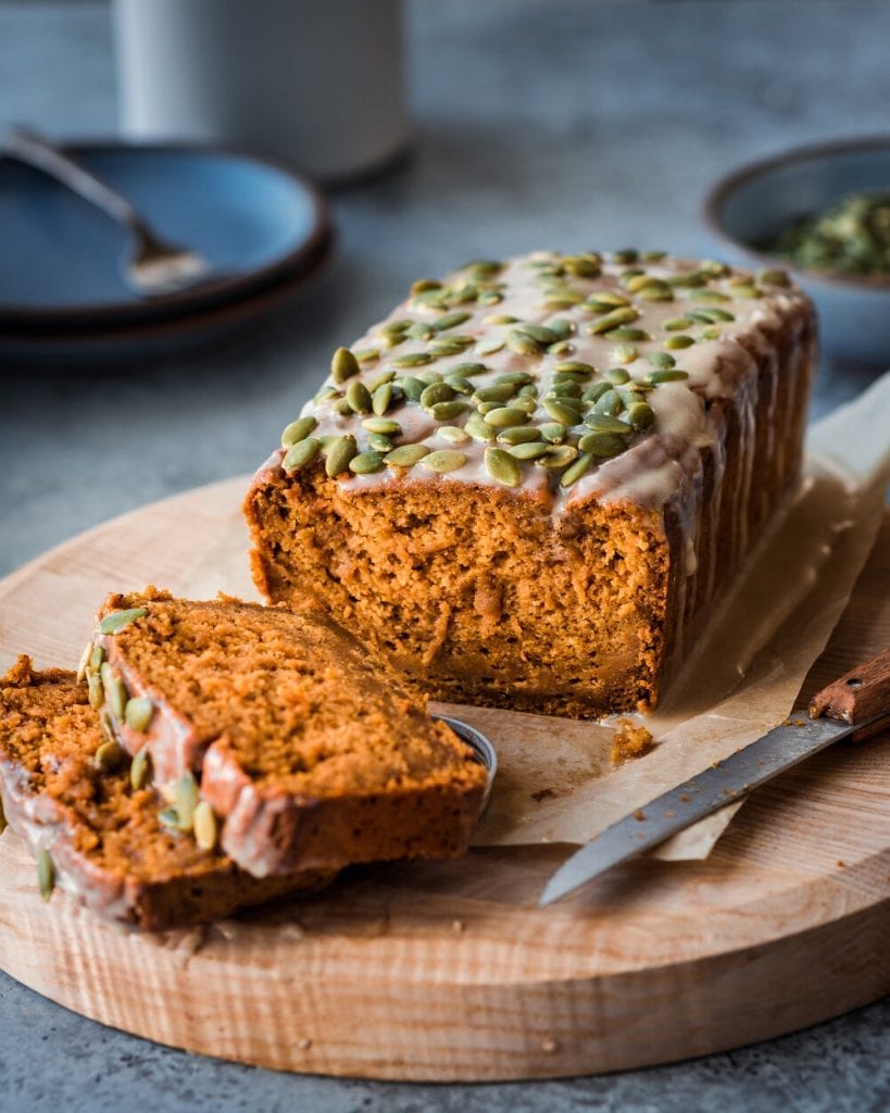 vegan pumpkin bread with icing on a wooden cutting board