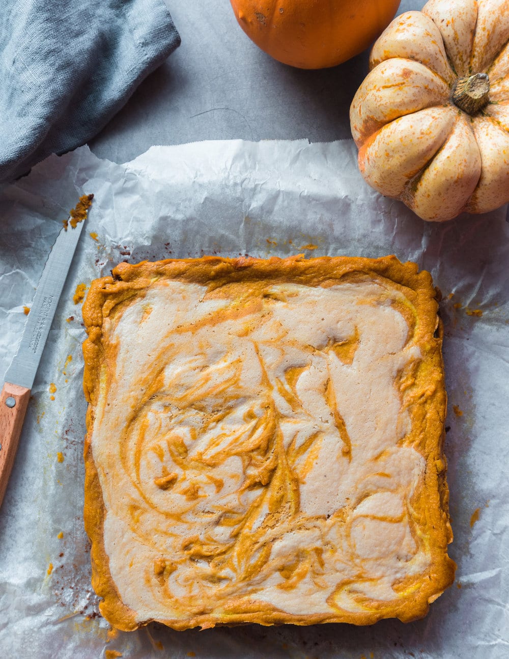 Full square unsliced pumpkin cheesecake on parchment paper.