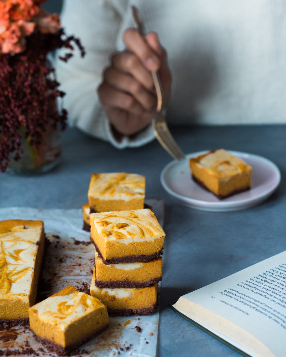 Woman eating cheesecake bar on a plate with fork.