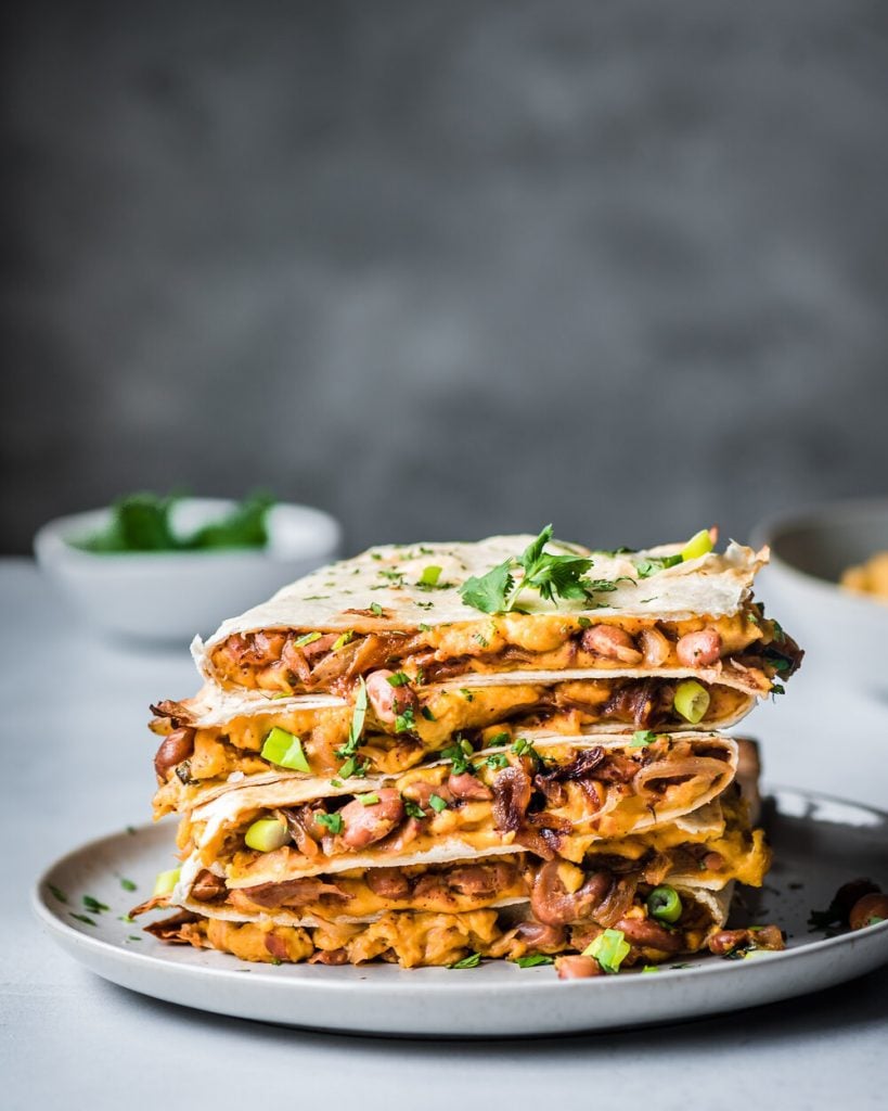 refried beans and vegan cheese quesadillas stacked on a plate