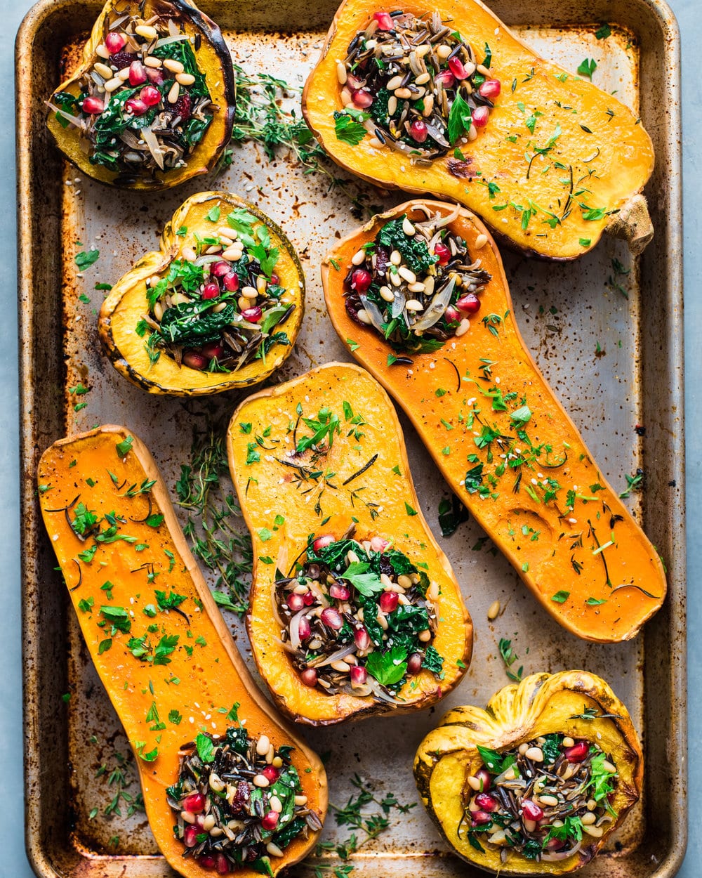 Seven stuffed roasted squash halves on a baking sheet on a grey table.