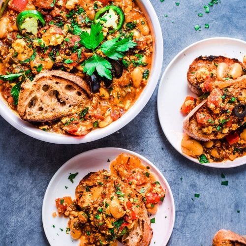 Two plates of shakshuka next to one large serving plate.