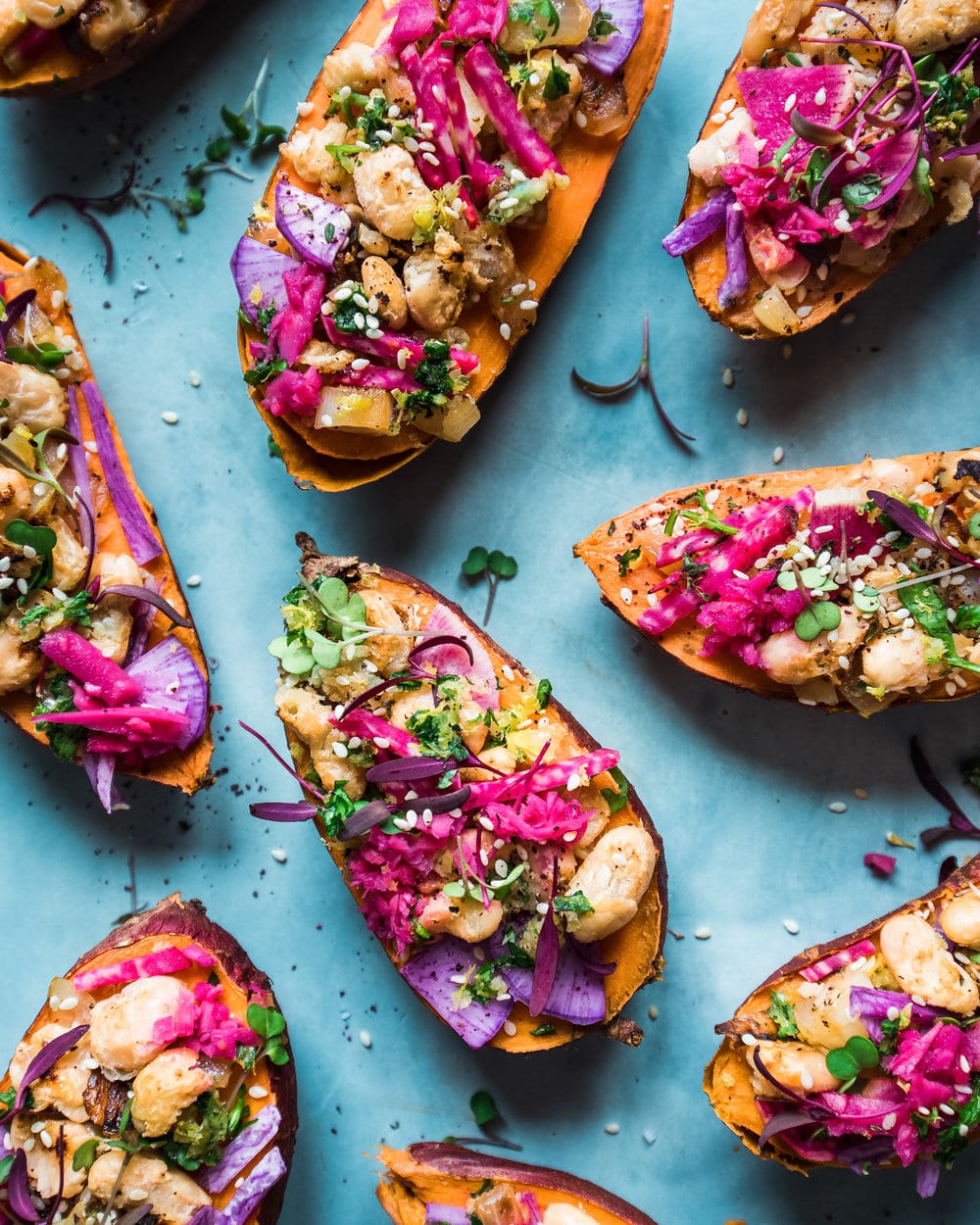 Nine tuffed sweet potatoes on blue table.