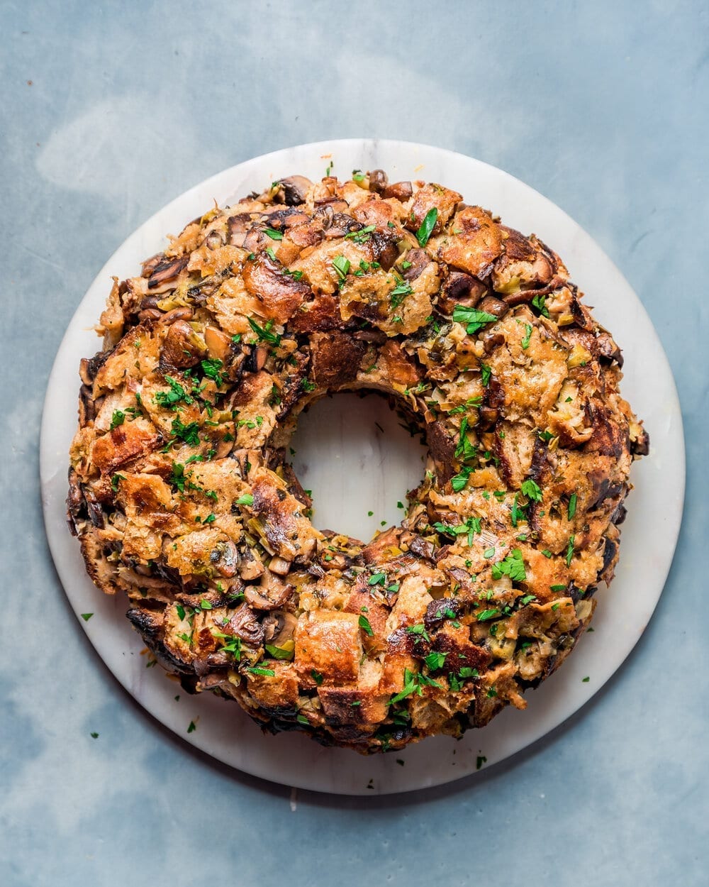 Overhead view of vegan mushroom stuffing wreath on a round marble serving board.