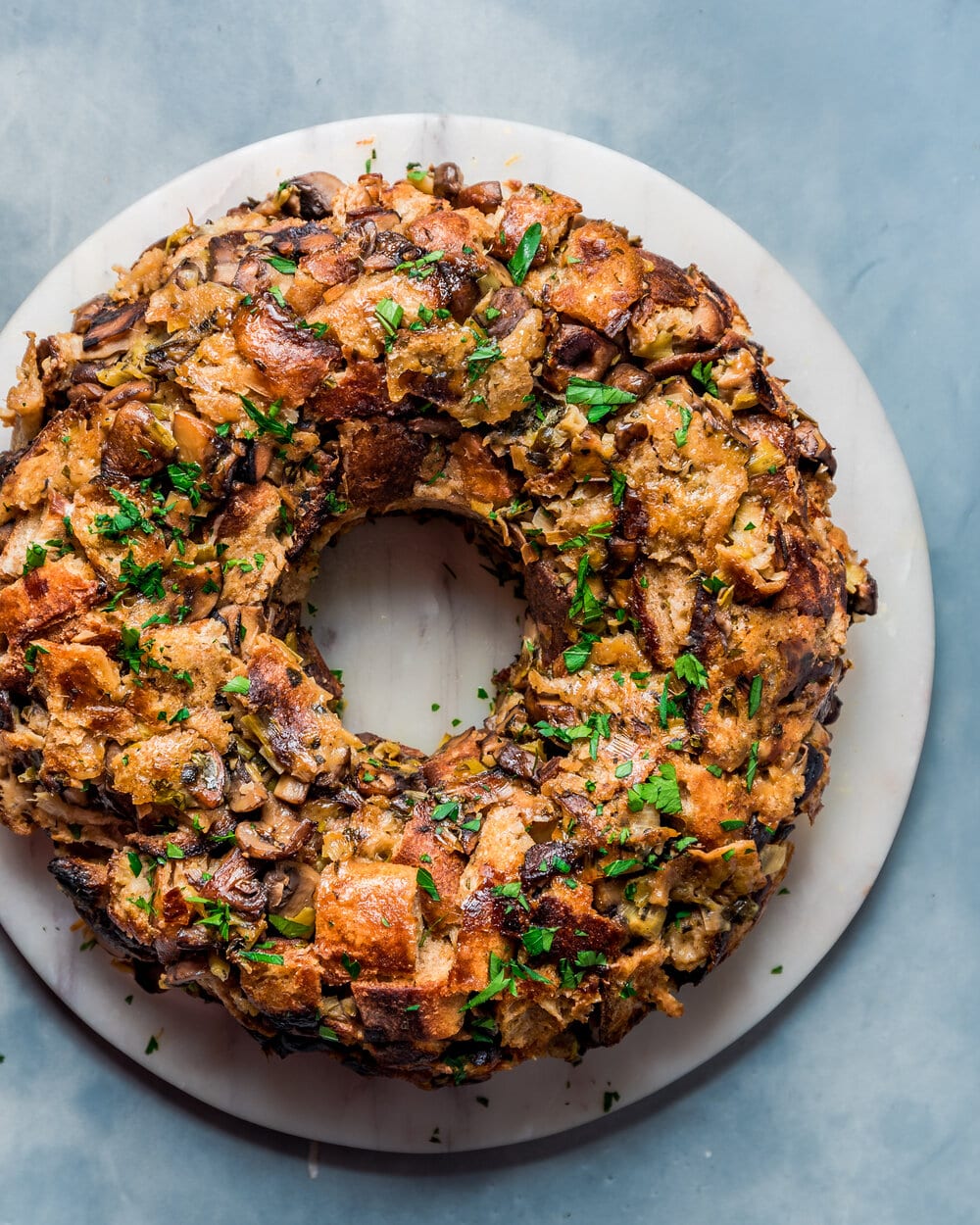 Overhead view of vegan mushroom stuffing wreath on a round marble serving board.