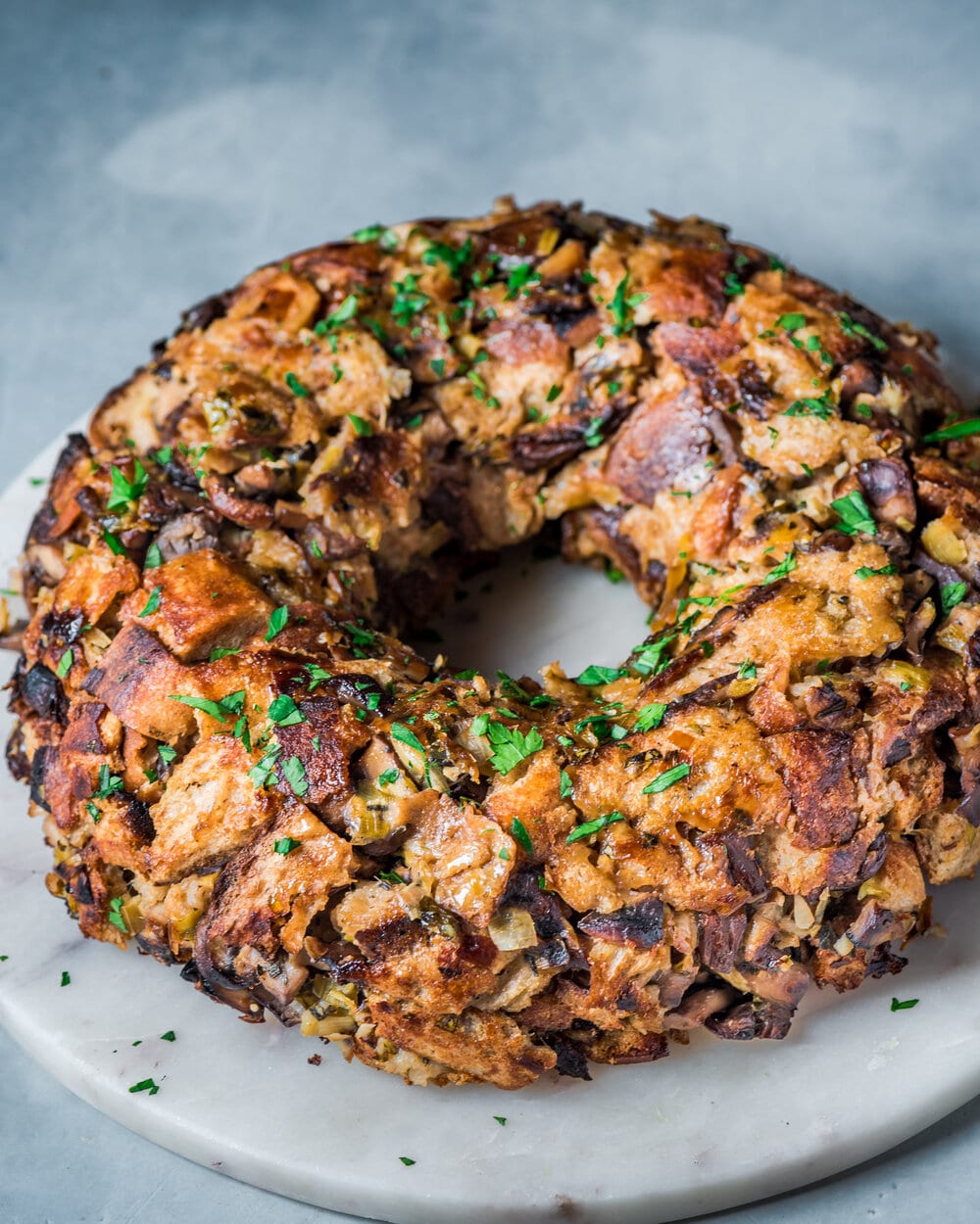 Side view of vegan mushroom stuffing wreath on a round marble serving board.