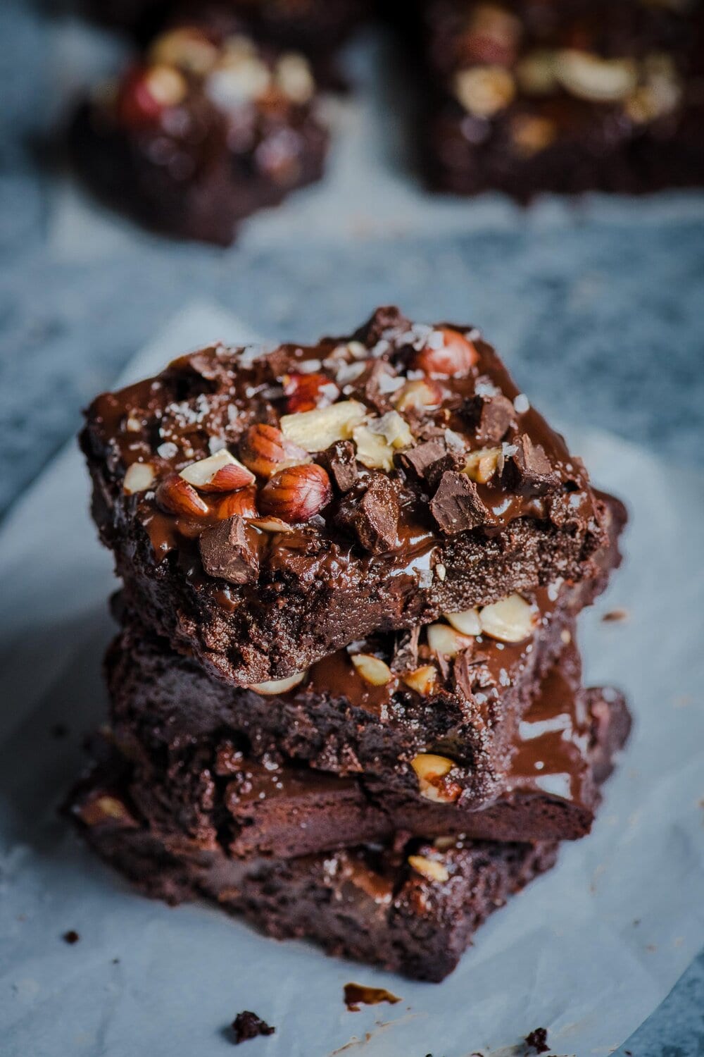 Three brownies stacked on one another on a grey table.