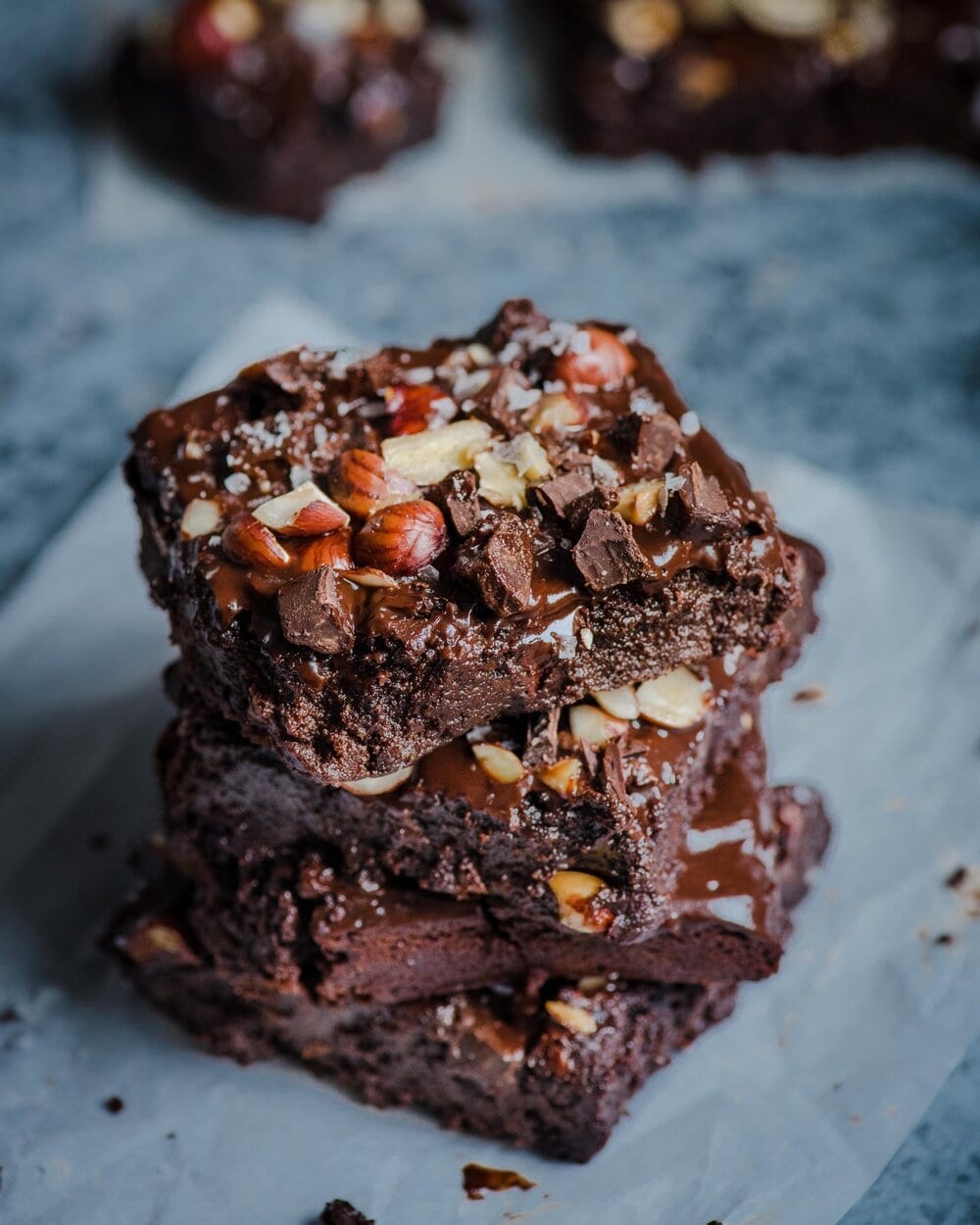 Three stacked brownies on a piece of parchment paper.