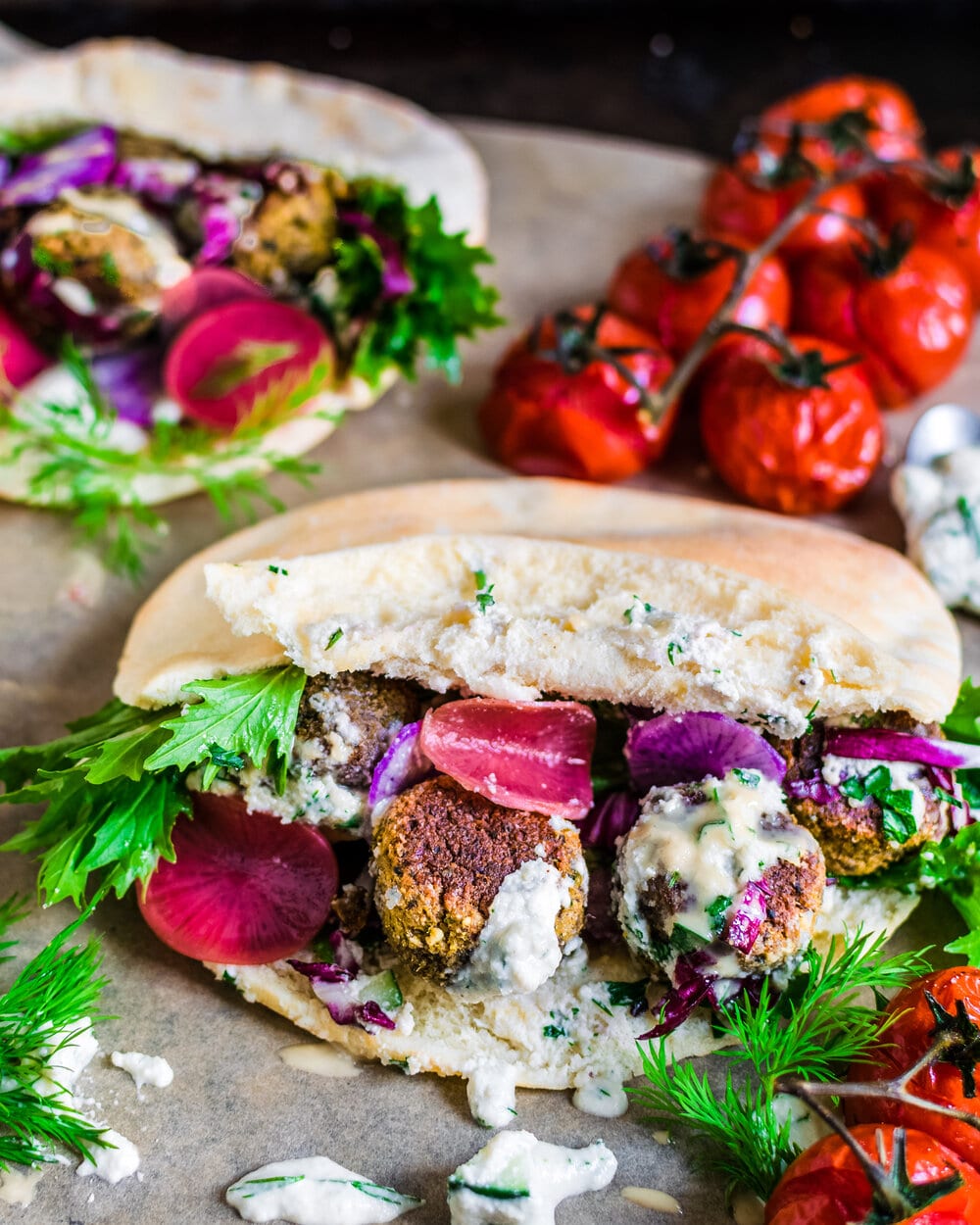 Side view of stuffed pita with falafel on parchment paper.