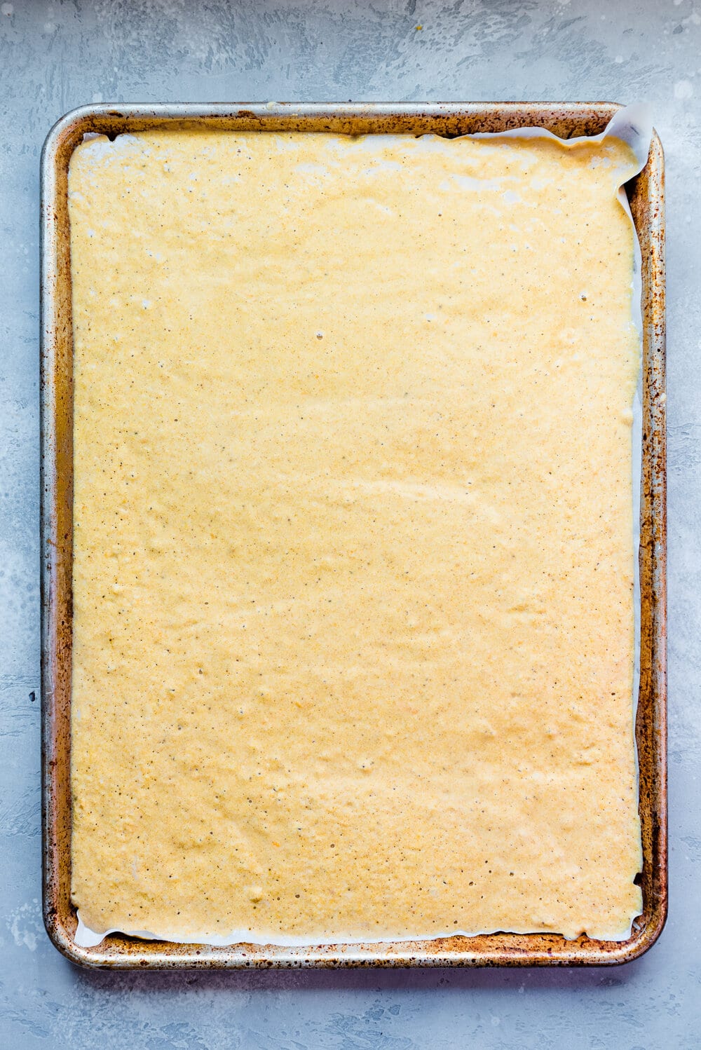 Pancake batter in a sheet pan lined with parchment paper.