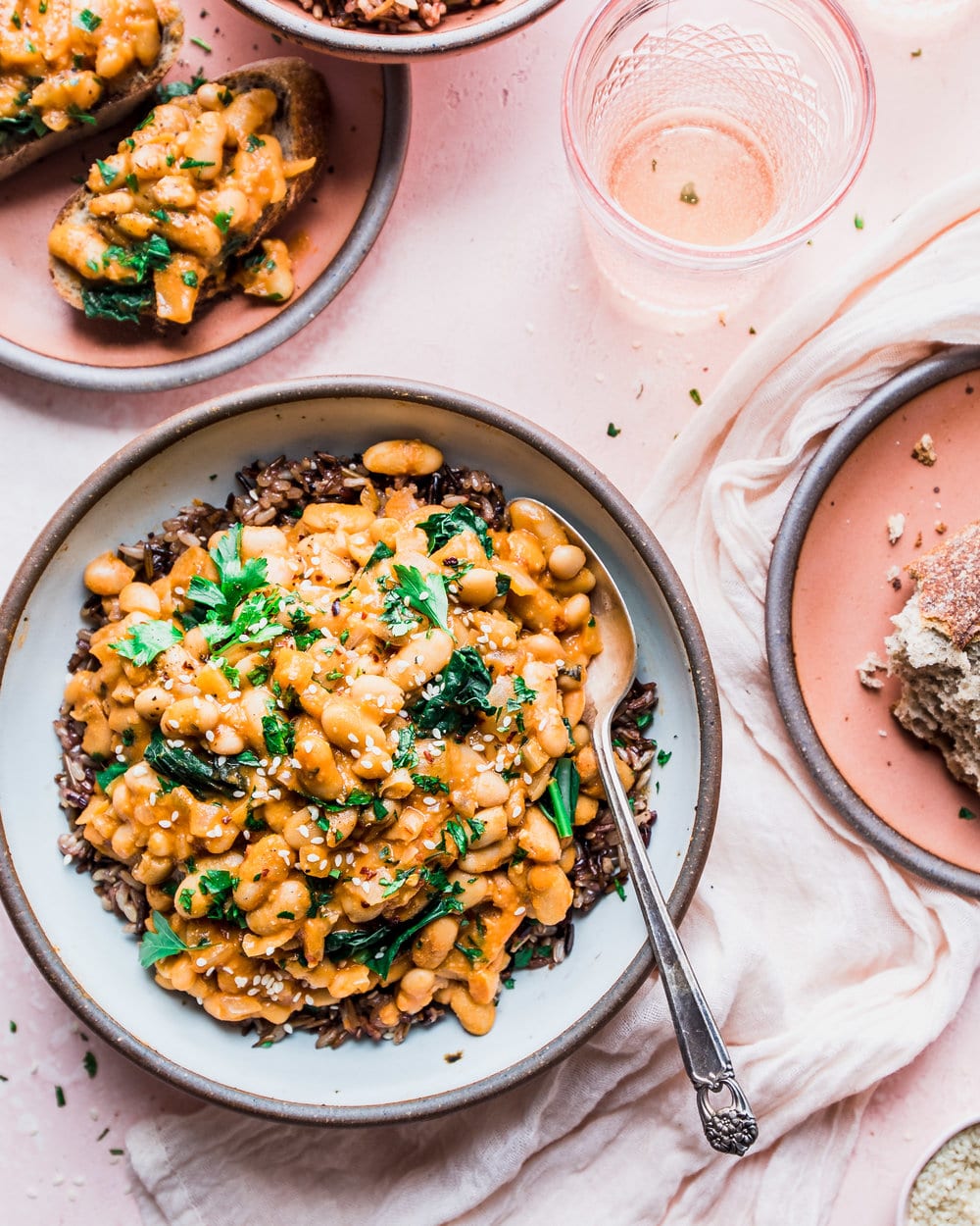 white bean kale stew in white bowl on pink backdrop