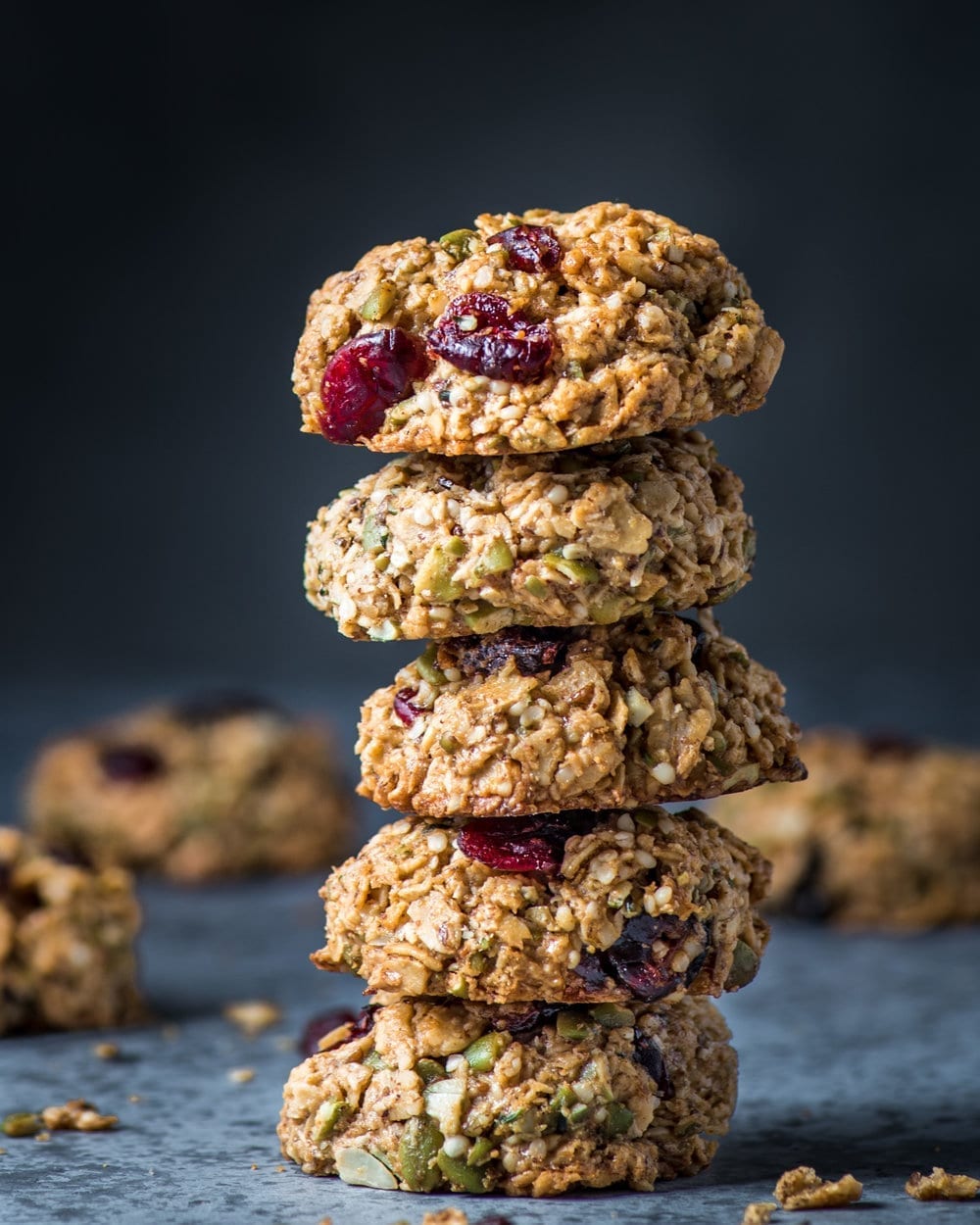 stack of five completed breakfast cookies against a dark background with cookies in the background