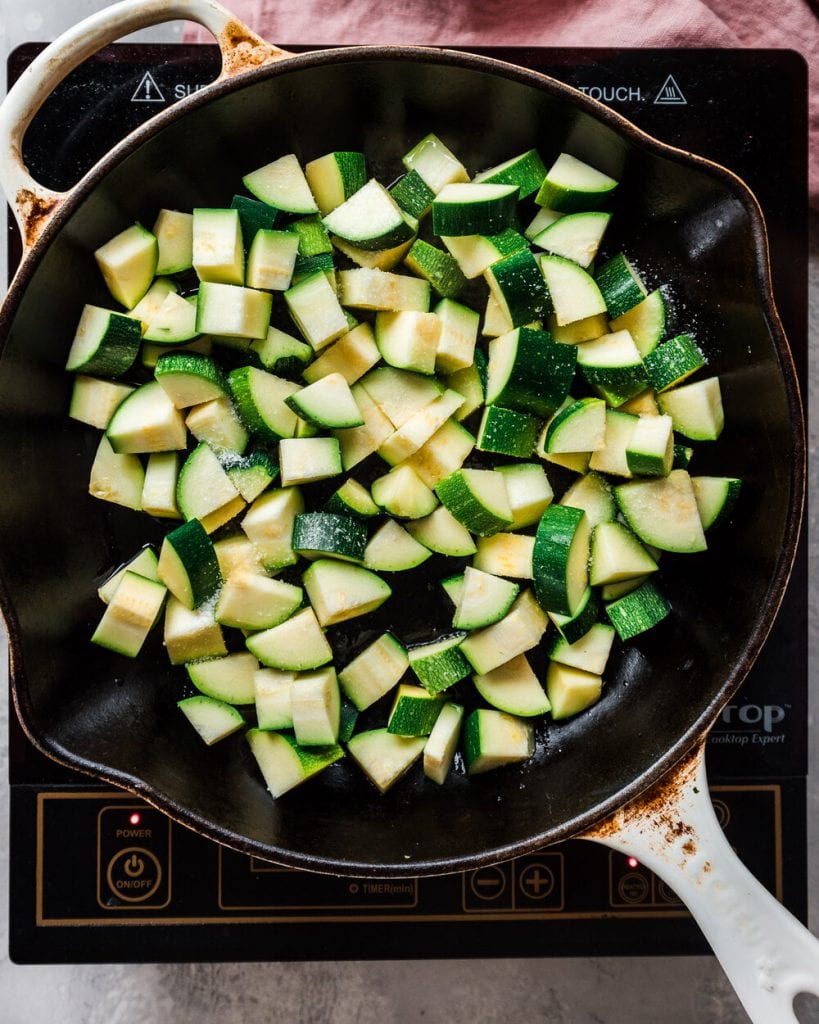 Zucchini sautéing in a cast iron skillet