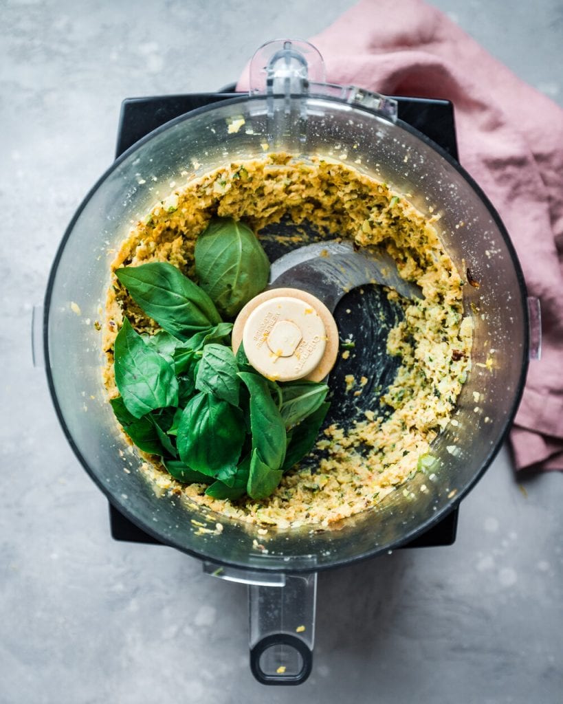 Spinach being added to pine nuts in food processor