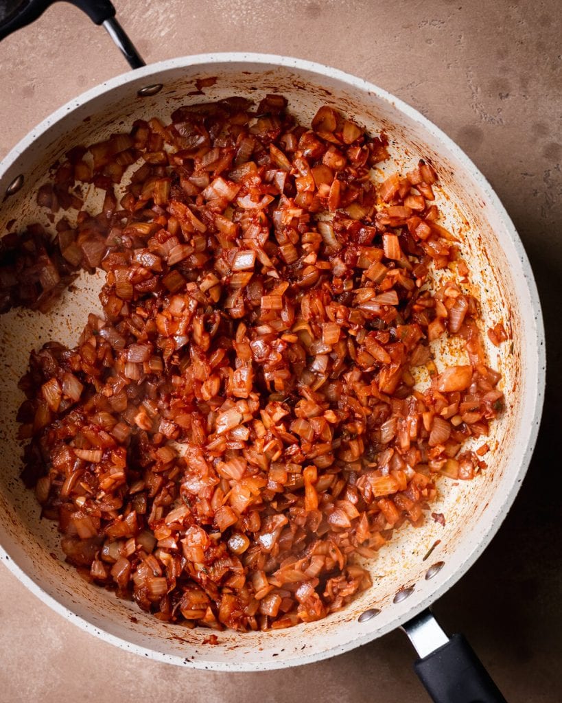 tomato paste added to cooked onion, garlic, rosemary and sage in saute pan