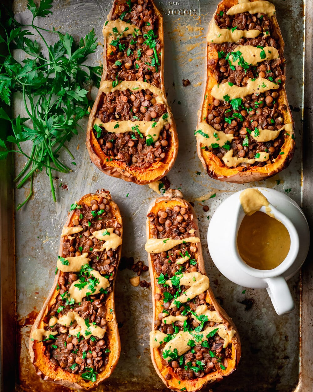 Four stuffed butternut squash halves on a baking sheet.