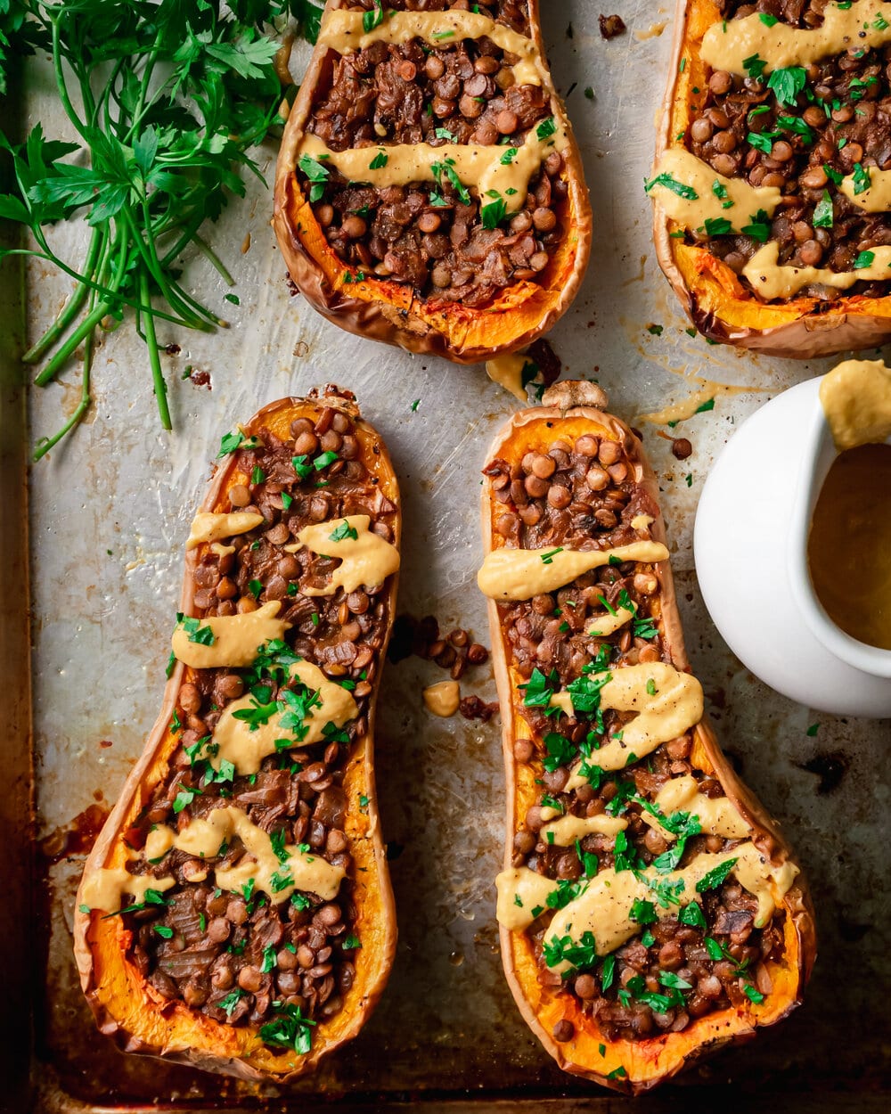 Lentil stuffed butternut squash halves on a baking sheet.