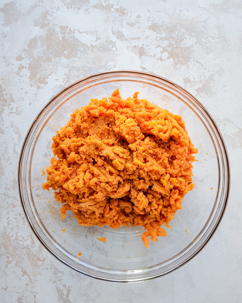 Mashed sweet potatoes in a glass bowl.
