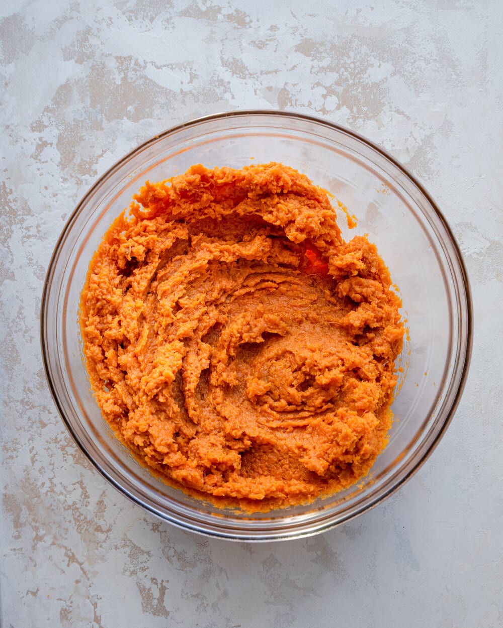 Mashed sweet potatoes in a glass bowl.