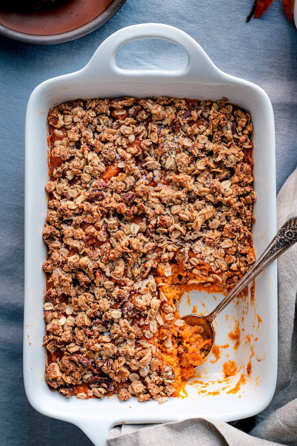 Full casserole dish with finished brown butter sweet potato casserole and a spoon.