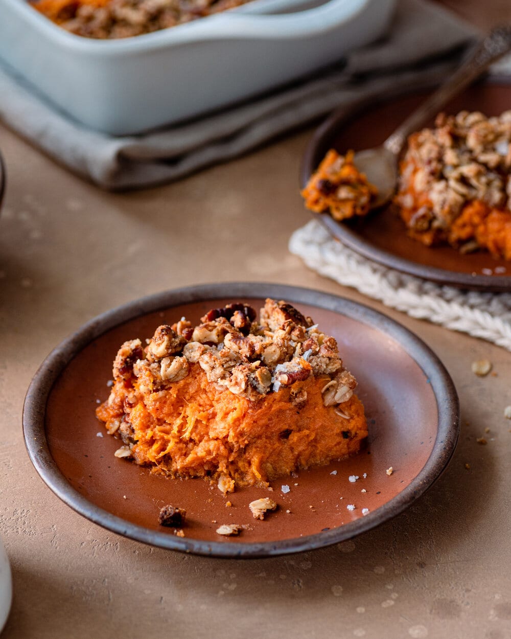 Piece of sweet potato casserole cut out and placed on a brown dish.