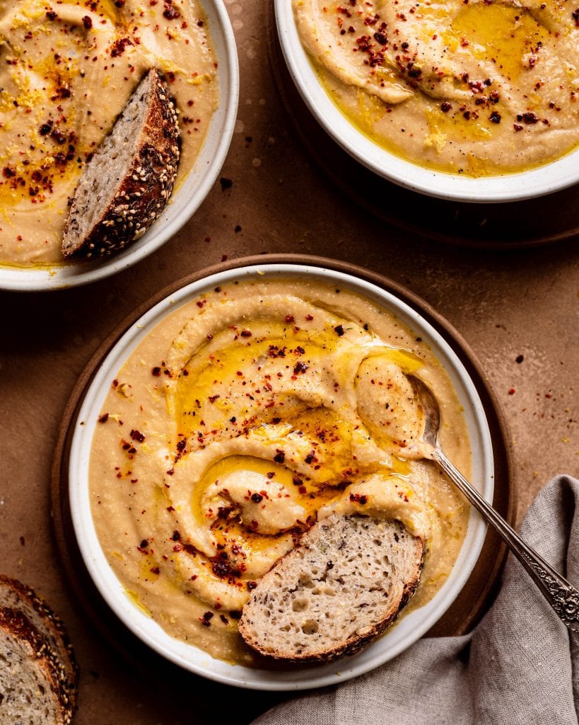 bowls of creamy vegan instant pot cauliflower soup with bread