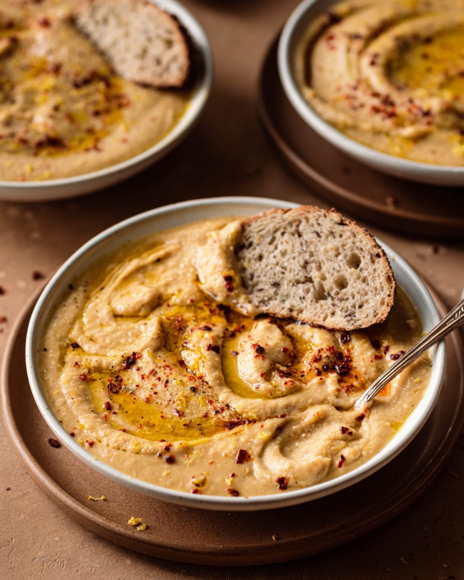 Bowl of creamy cauliflower soup with a piece of crusty bread in it.