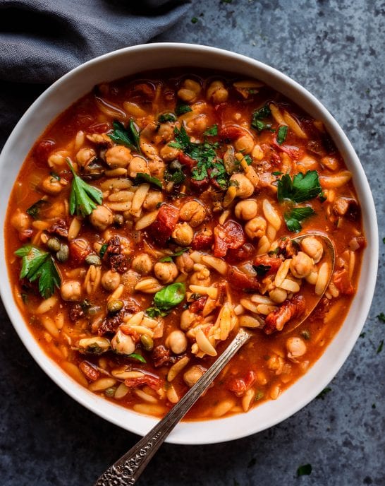 Instant Pot Chickpea Orzo Soup in white bowl with spoon.