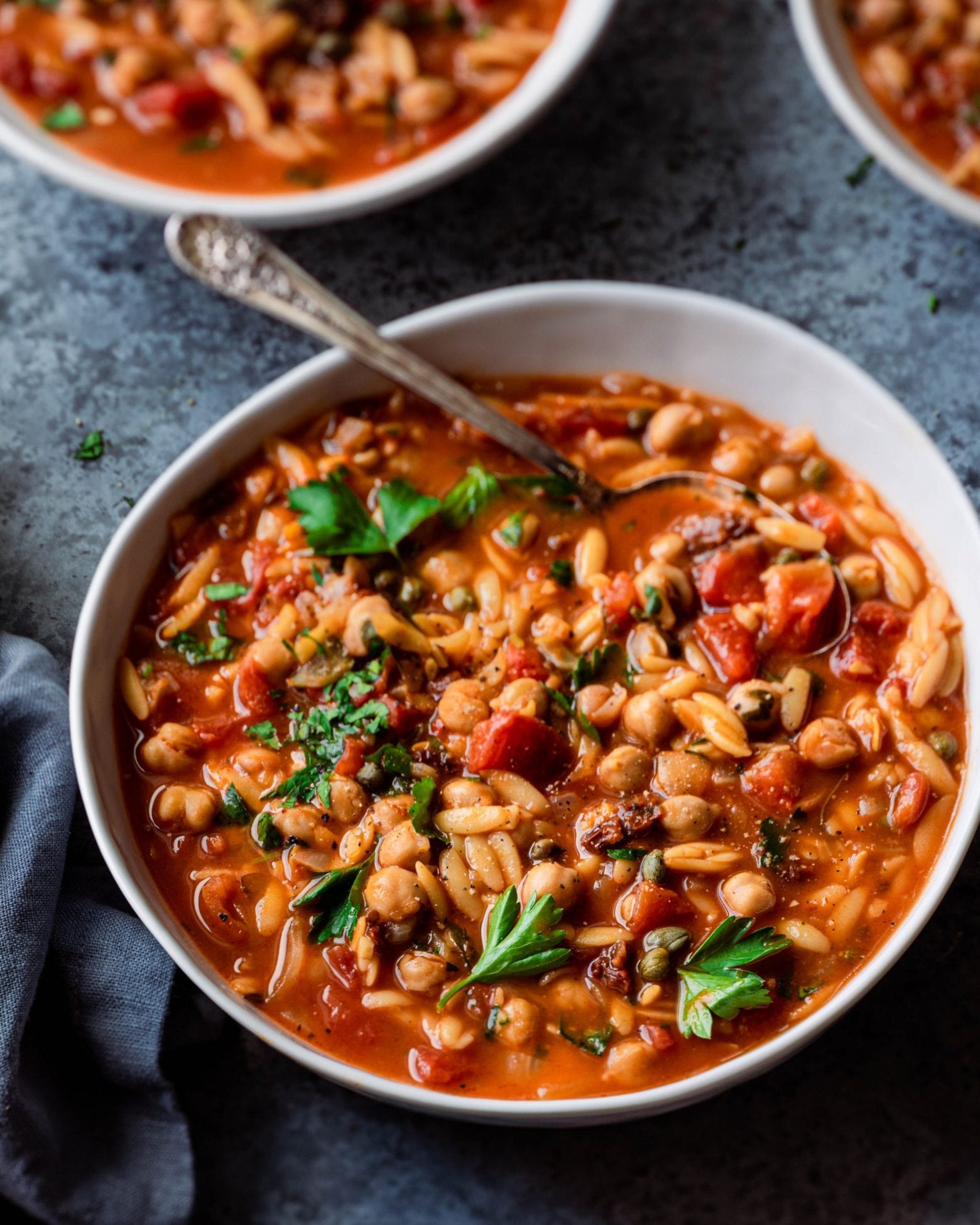 tomato orzo chickpea soup in bowl with spoon