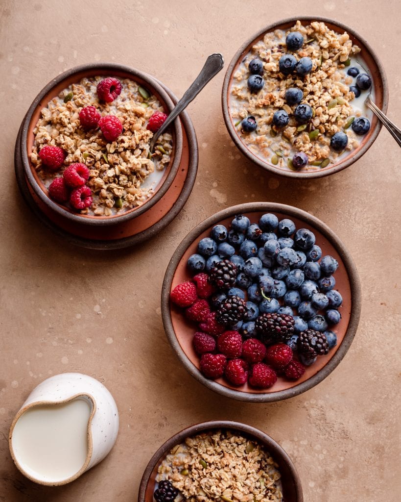 Veganuary Tips. bowls of granola with milk and berries on brown board