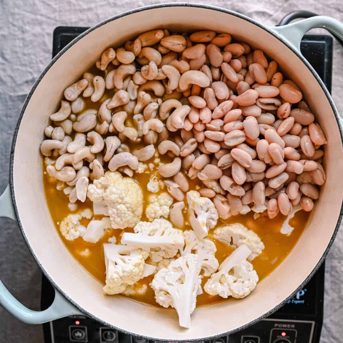 cauliflower florets, cashews and white beans in broth for soup