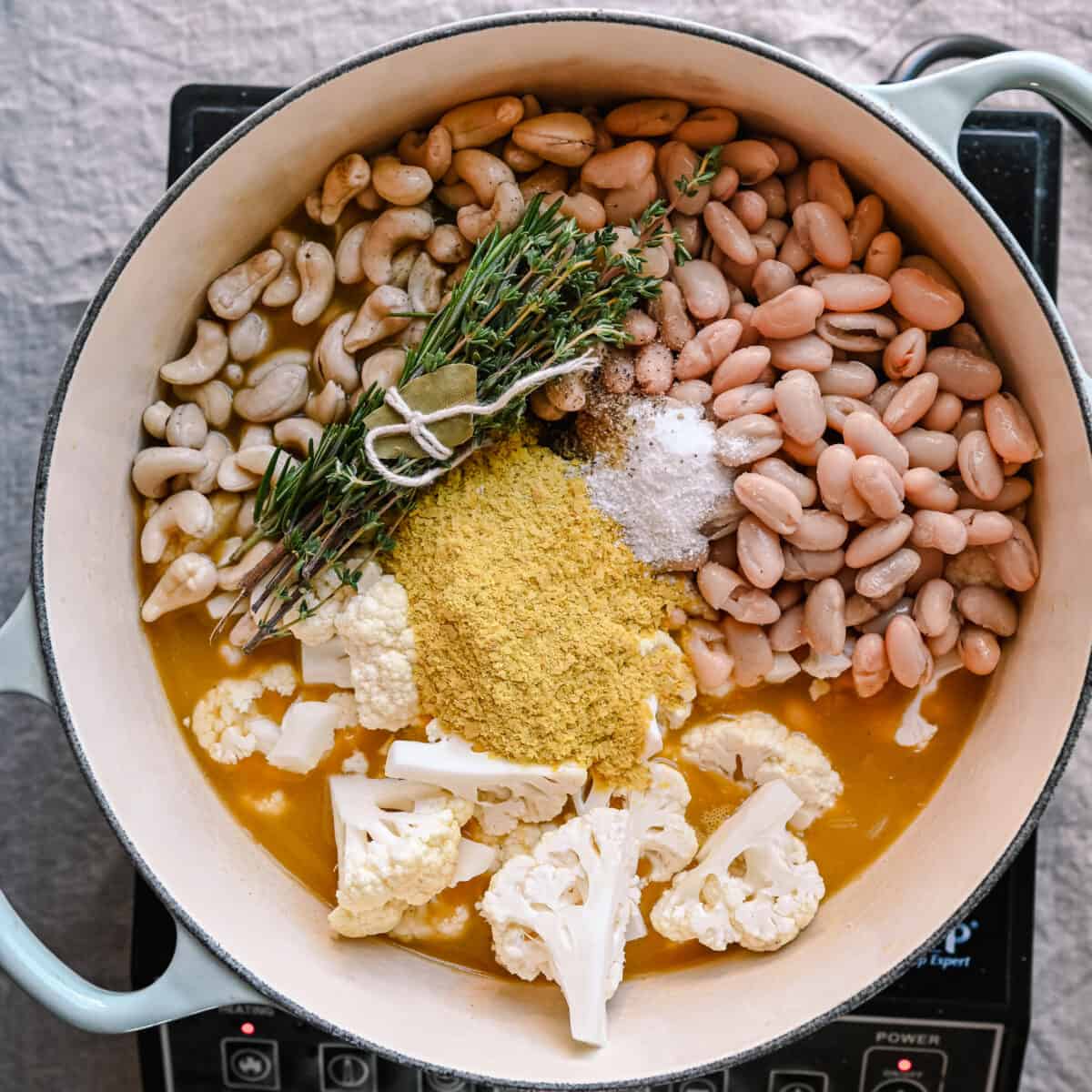 cauliflower florets, nutritional yeast, bouquet garni, cashews and white beans in broth for soup