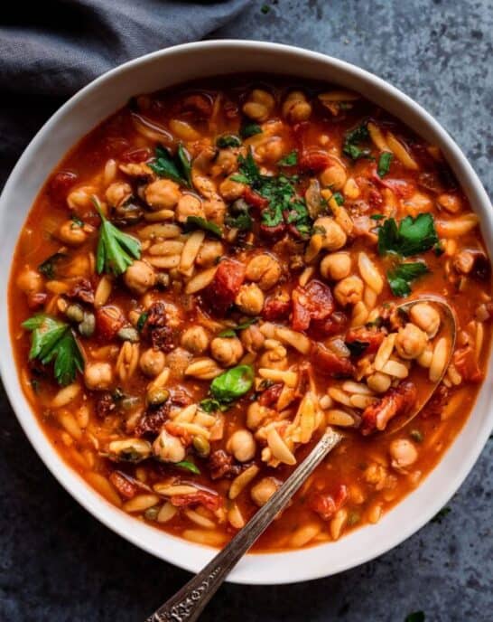 Instant Pot Chickpea Orzo Soup in white bowl with spoon.
