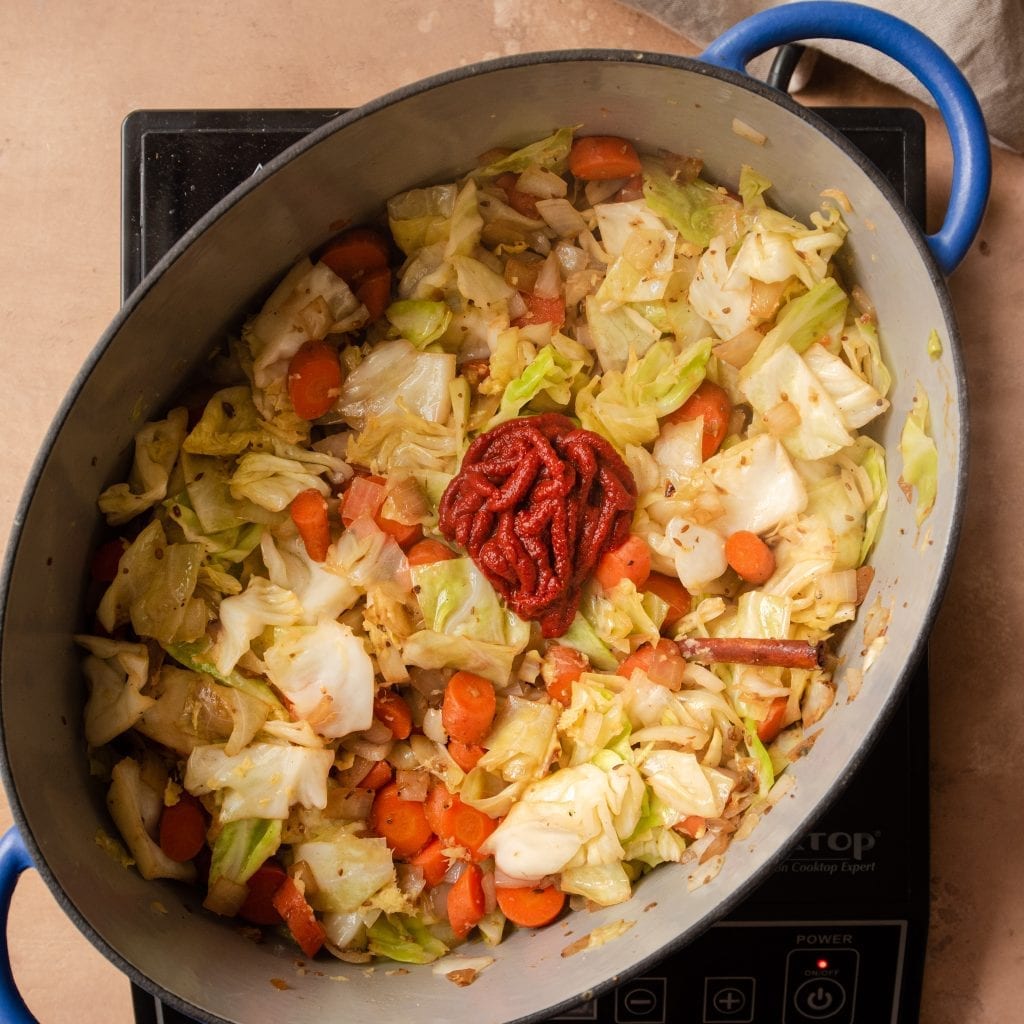 tomato paste on top of cabbage and carrots in dutch oven