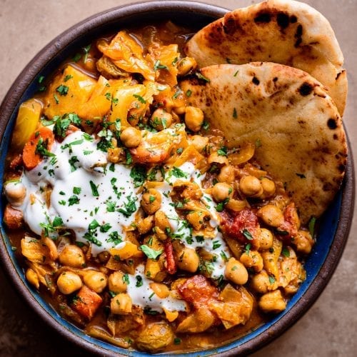 bowl of indian chickpea stew with yogurt and naan
