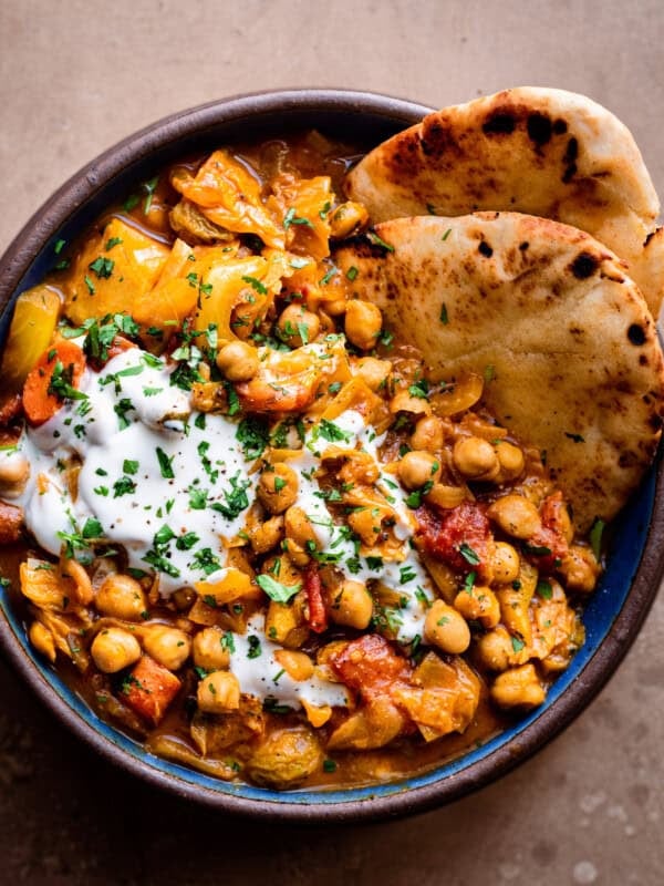 bowl of indian chickpea stew with yogurt and naan
