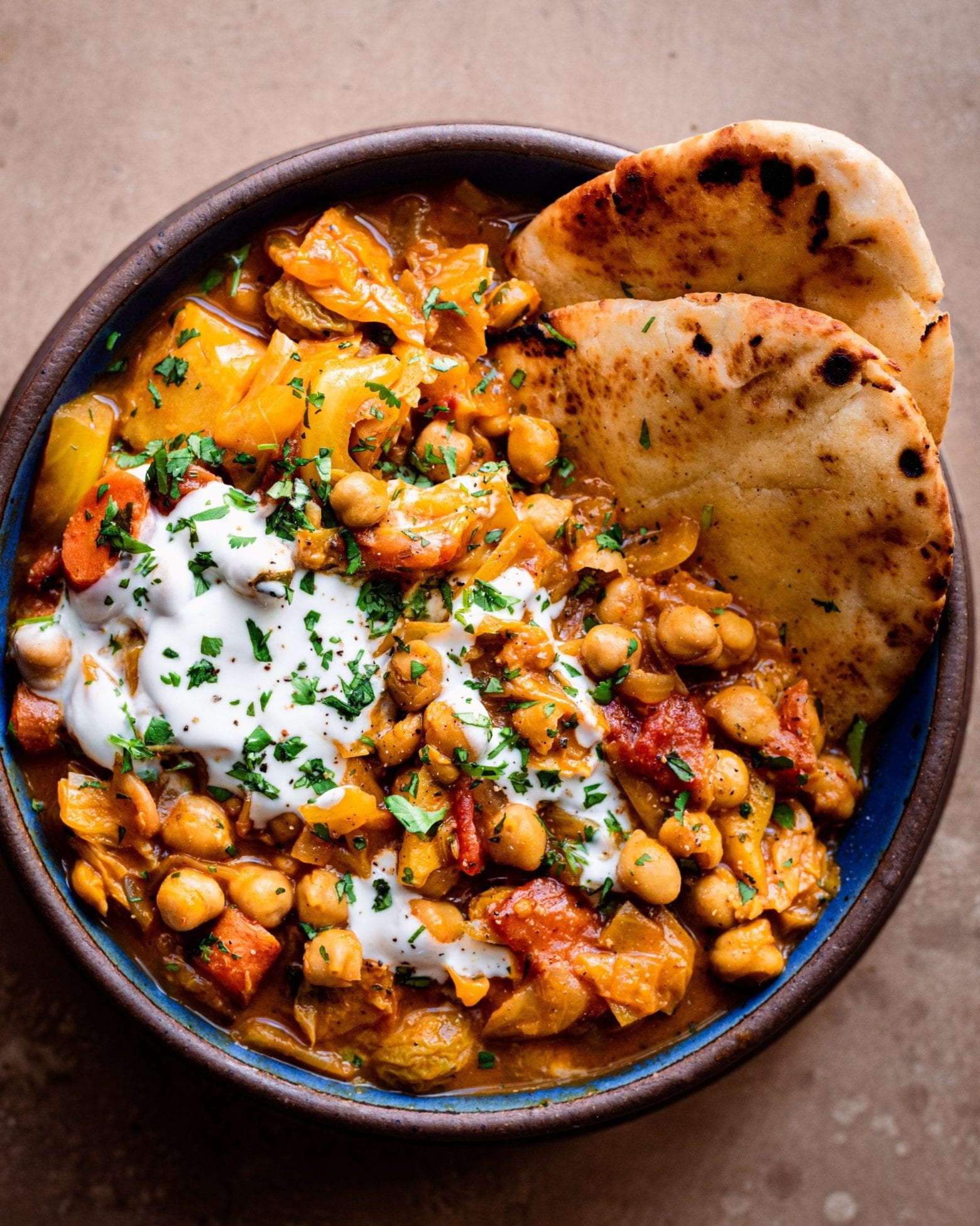 bowl of indian chickpea stew with yogurt and naan