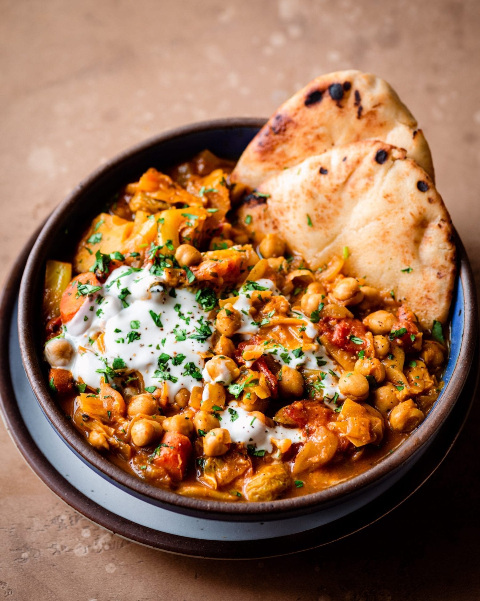 indian chickpea stew in a bowl with naan and yogurt