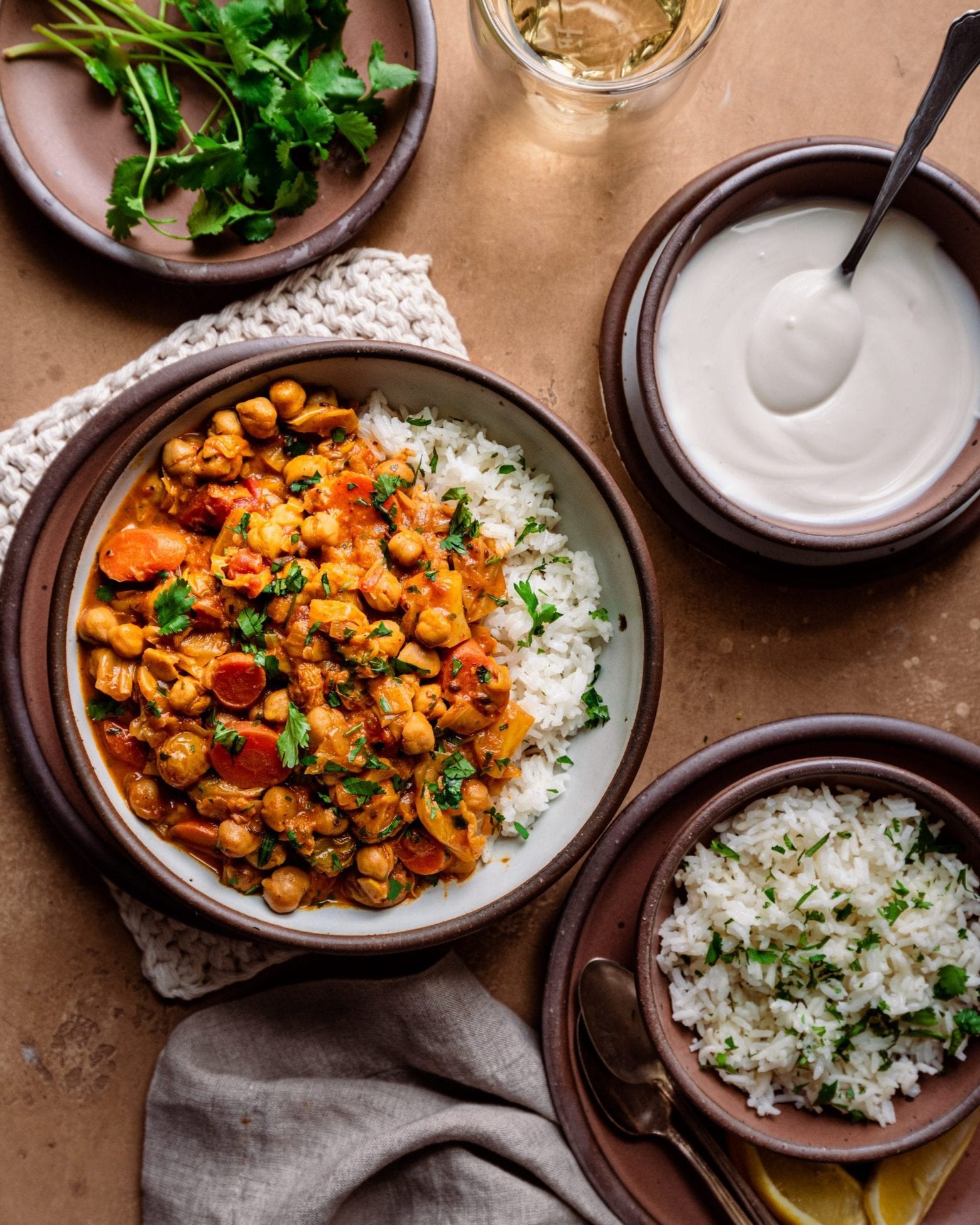 dinner scene with indian chickpea stew, rice, yogurt, and cilantro
