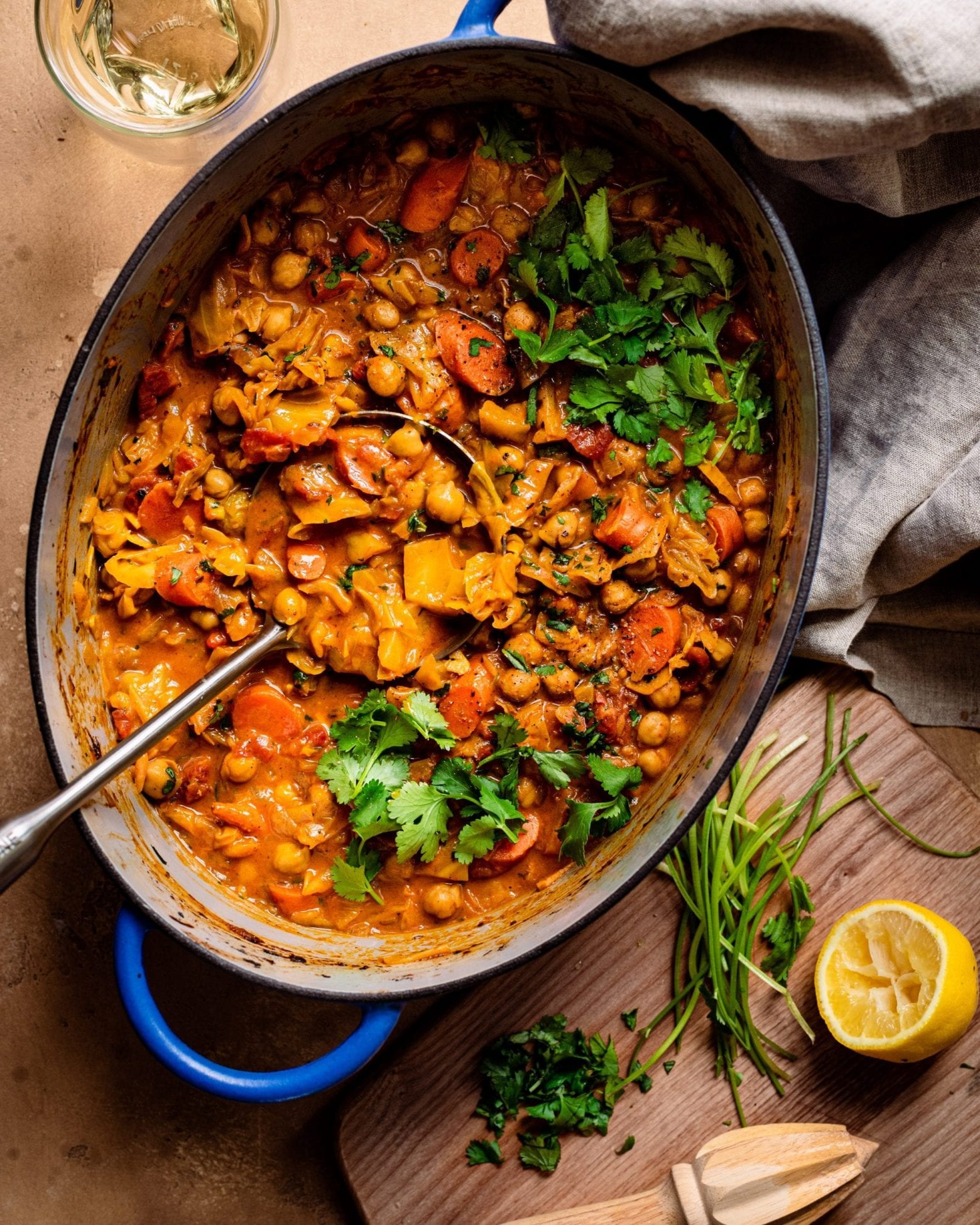 dutch oven with ladle of chickpea stew and cutting board with garnishes