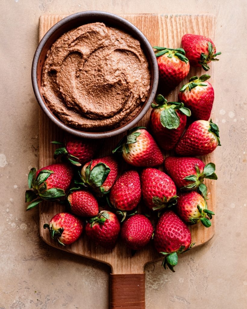 cutting board with strawberries and chocolate hummus dip