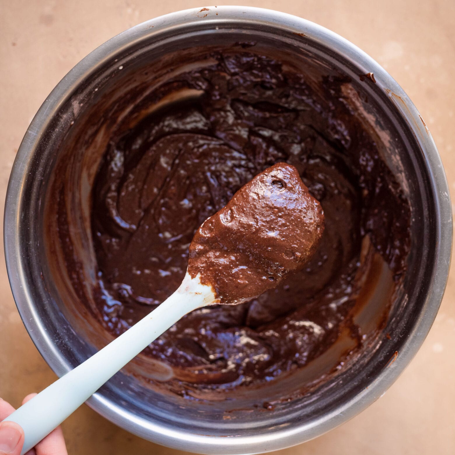rich, thick vegan brownie batter in a mixing bowl with spatula